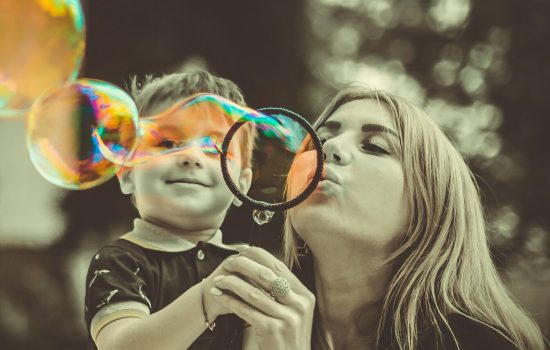 Mutter mit Kind bläst Seifenblasen