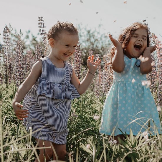 Zwei Mädchen lachend in Blumenwiese